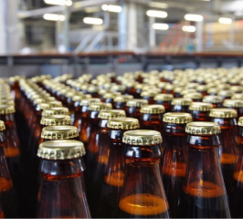 rows of glass bottles with metal pop off caps on a conveyor belt